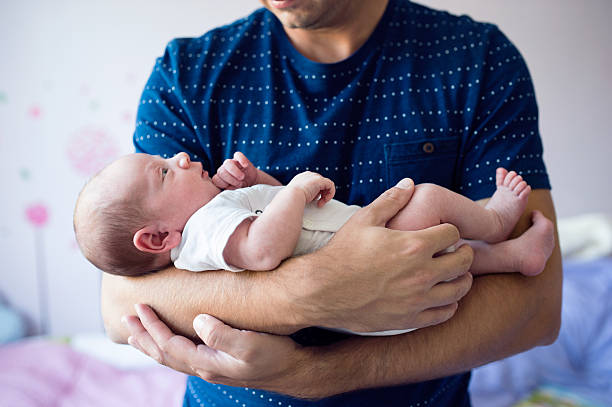 close up of unrecognizable father holding his newborn baby son - newborn human hand baby father imagens e fotografias de stock