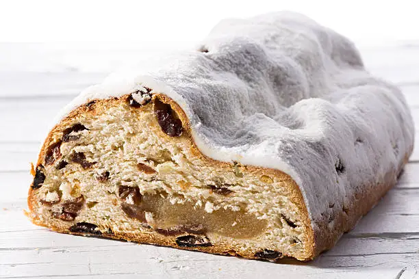 Christmas stollen with raisins and marchpane on white wooden background