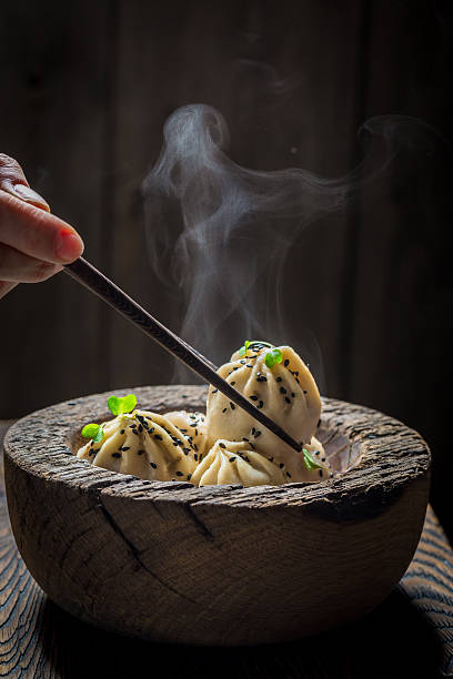 hausgemachte und heiße chinesische knödel in holzschale - chinese dumpling vertical dumpling asian culture stock-fotos und bilder