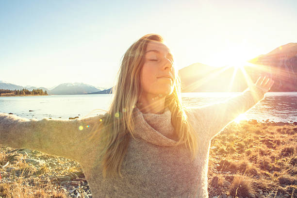 mujer joven relajándose junto al lago, aire fresco de montaña - lake tranquil scene landscape zen like fotografías e imágenes de stock