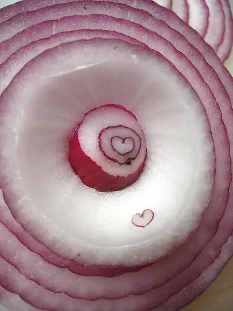 A raw sliced red onion revealing a naturally found heart shape in the center