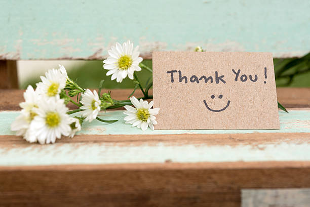 dankeschön-note mit lächeln gesicht und blumenhaufen - text schriftsymbol stock-fotos und bilder