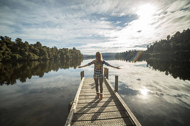 mulher jovem relaxa no lago cais, de pé com os braços esticados - lake tranquil scene landscape zen like - fotografias e filmes do acervo