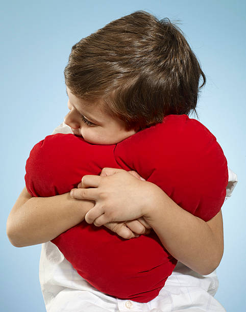 Little boy holding red heart.
