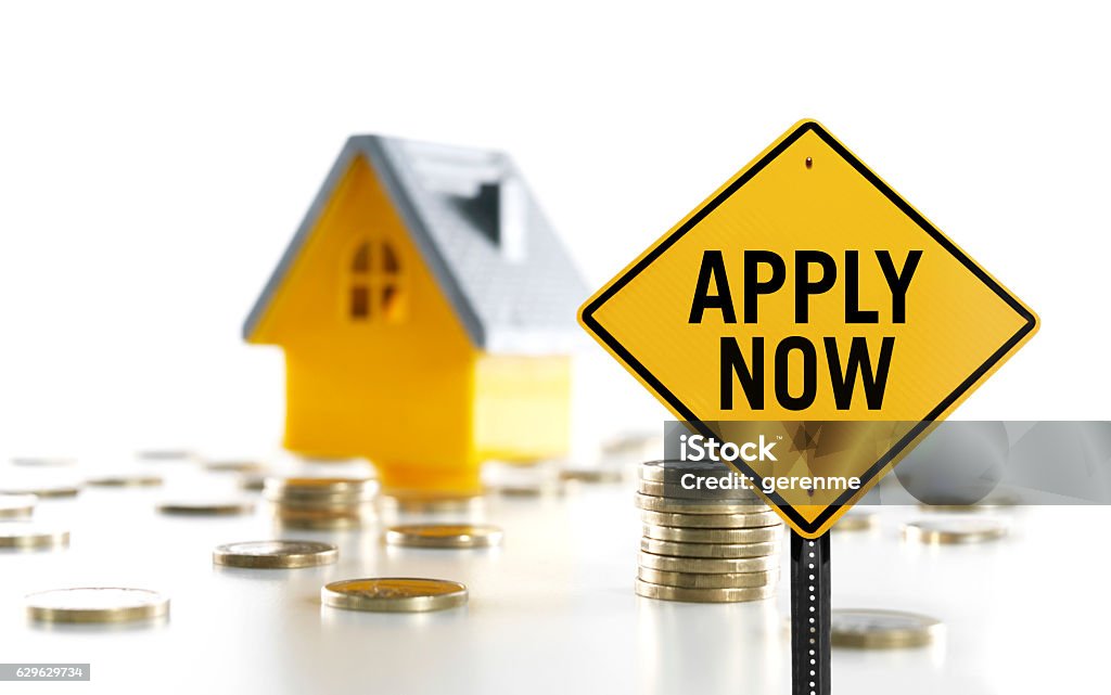 Apply now Apply now sign in front of a toy house and money coins Apply Now Stock Photo