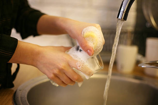 istock Close up of two hands washing dishes. 629638850