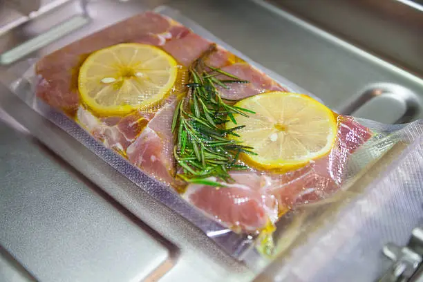 Sous-vide. Beefsteak in olive oil with rosemary and lemon in vacuumed package.