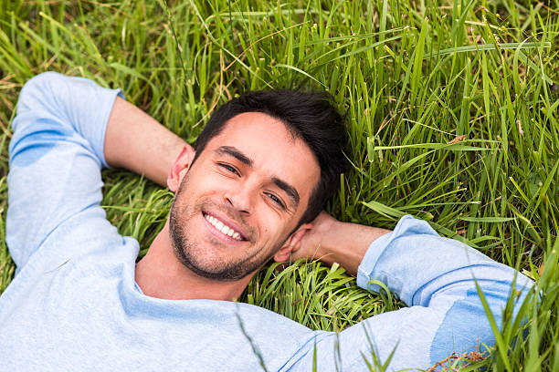 istock Happy handsome smile young man lying on the green grass 629640356