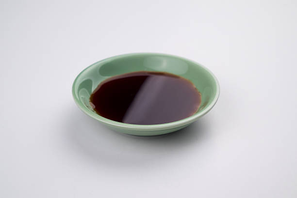 Soy sauce in a saucer. Single serving. Photographed on white background.