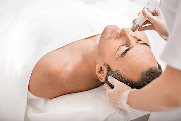 Professional beautician rejuvenating male face