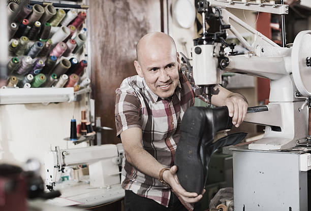 istock Mature workman sewing leather boots on stitch lathe 629656588