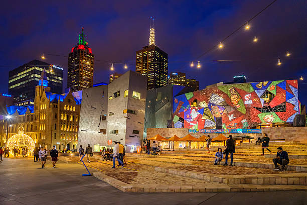 Melbourne, Australia - December 14, 2016: Visitors around Federation Square. A building has a Christmas design projected on its facade to commemorate the upcoming holiday.