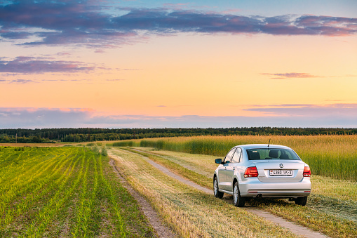 Gomel, Belarus - June 6, 2016: Volkswagen Polo Car Parking On Wheat Field. Sunset Sunrise Dramatic Sky On A Background In Sunny Evening.
