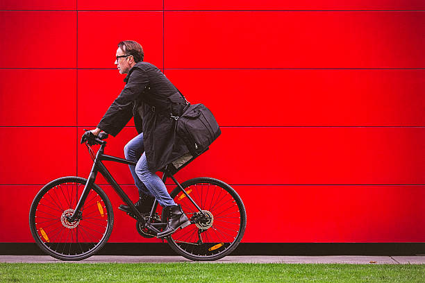 hübscher mann reiten fahrrad am roten wand - cycling bicycle healthy lifestyle green stock-fotos und bilder