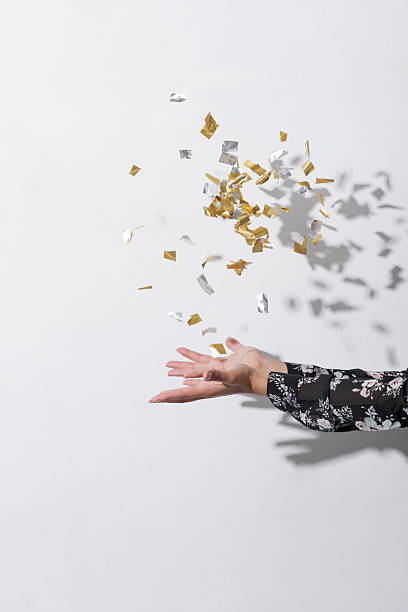 Hands of unrecognizable woman throwing golden confetti
