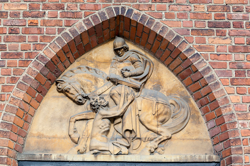 Detail of a bas relief on the facade of the gothic St Martin of Tours church brick historical building in Poznan, Poland.