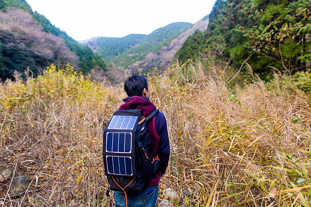 Man walking into wilderness with solar cells on his backpack stock photo