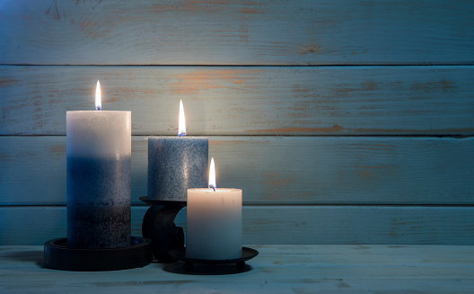This is a photo of three candles on a ship wood background. The focus is on the flame in the front and falls off quickly. This image could work well for Christmas, Hanukah, Easter, Health spas, etc.