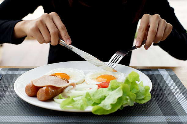 istock woman hands holding knife and fork during eating breakfast 629680598
