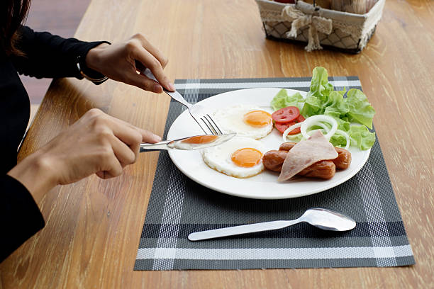 istock woman hands holding knife and fork during eating breakfast 629680766