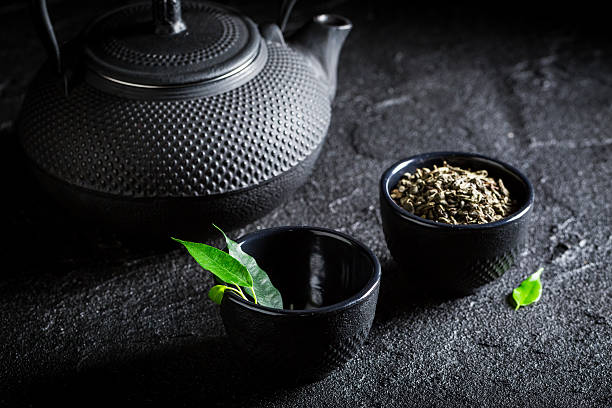 istock Tasty green tea with teapot and cup on black rock 629688466