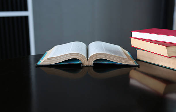 istock Open book and hardcover books on wooden table in library. 629690320