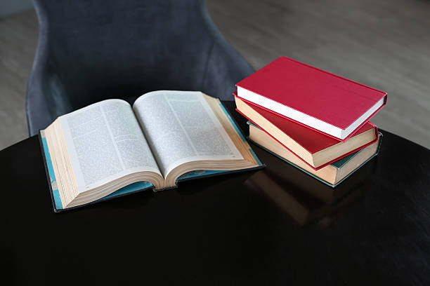 istock Open book and hardcover books on wooden table in library. 629690404