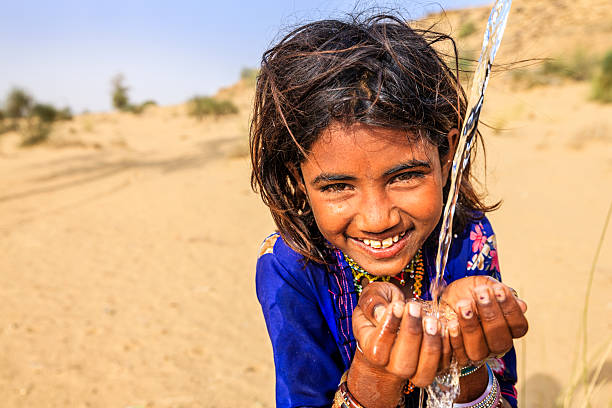 Indian little girl drinking fresh water, desert village, Rajasthan, India Indian little girl is drinking fresh water, desert village, Thar Desert, Rajasthan, India. Potable water is very precious on the desert - Rajasthani women and children often walk long distances through the desert to bring back jugs of water that they carry on their heads.  developing countries photos stock pictures, royalty-free photos & images