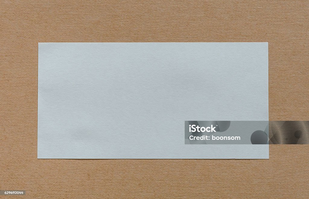 Blank white paper label on cardboad background Blank white paper label on brown cardboad background Paper Stock Photo