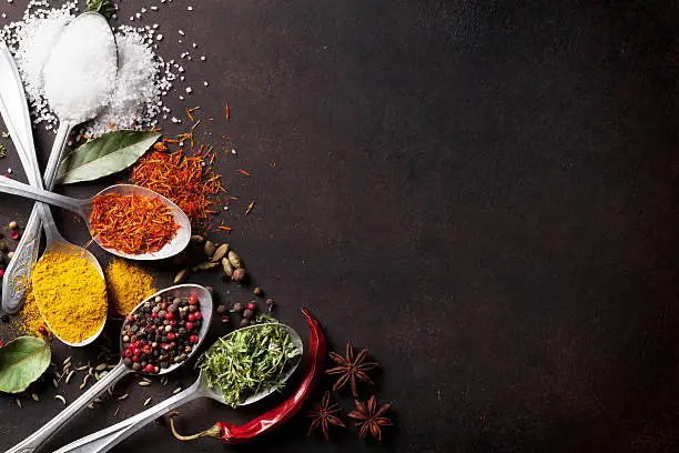 Photo of Various spices spoons on stone table