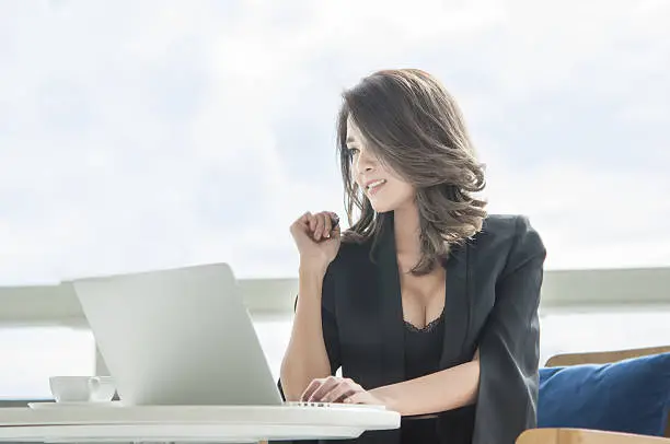 Asian businesswoman to happy work with laptop in office and imagine at work success