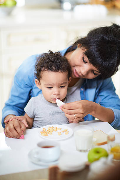 кормление сына - baby eating child mother стоковые фото и изображения