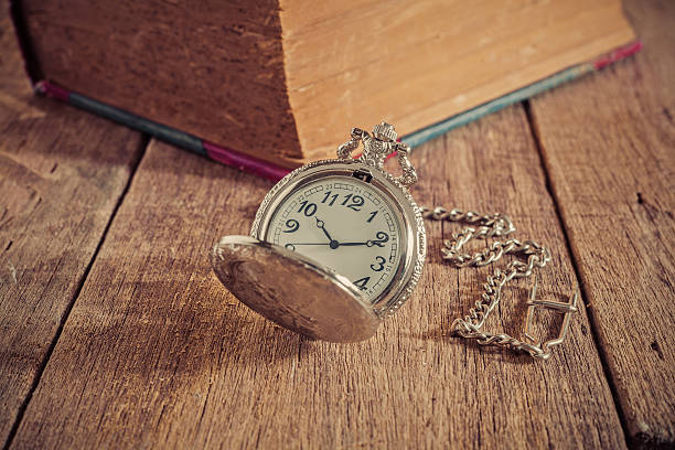 istock vintage pocket clock and old books on wood table 629713752