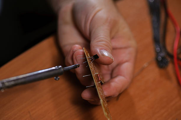 istock Male hands with soldering iron and microcircuit. 629714180