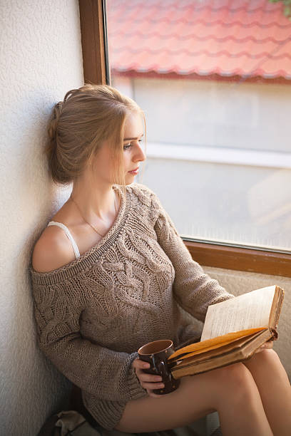 istock Young beautiful woman reading by the window. 629718680