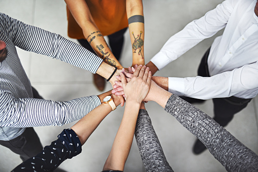 Cropped shot of a group of colleagues joining their hands together in unity