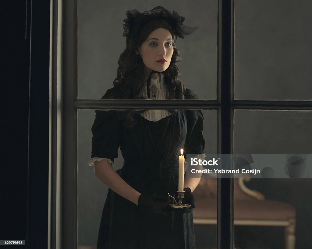 Retro viktorianischen Frau in schwarzem Kleid hinter dem Fenster hält Kerze. - Lizenzfrei Frauen Stock-Foto