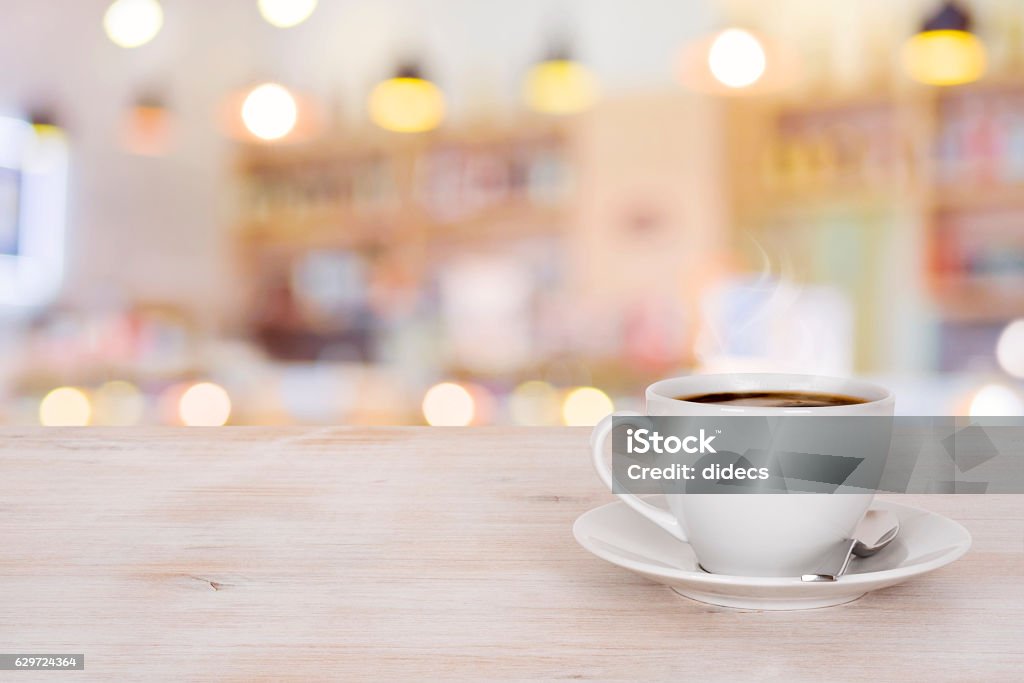 Coffee cup on wooden table over defocused cafeteria background Table Stock Photo