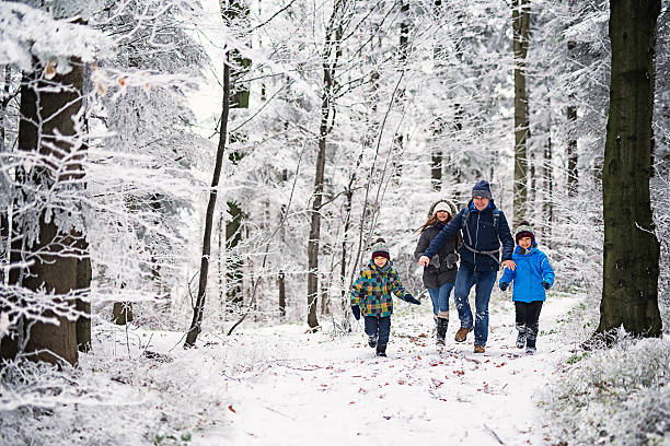 Father with kids running in beautiful winter forest Father with three kids running in beautiful winter forest. The little girl is aged 10 and her brothers are aged 7. Cold winter day  snow hiking stock pictures, royalty-free photos & images