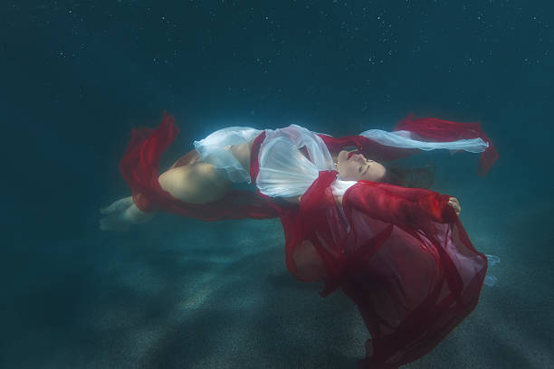 istock Woman in red dress dancing underwater. 629725308