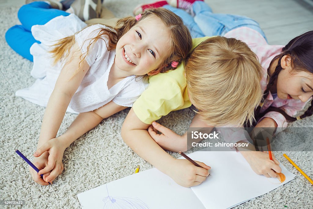 Happy girl Smiling girl looking at camera with her friends drawing near by Art Stock Photo