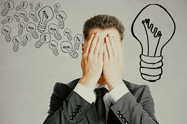 Idea concept Businessman covering face with palms on grey background with creative lamp drawings. Idea concept man with a light bulb over his head stock pictures, royalty-free photos & images