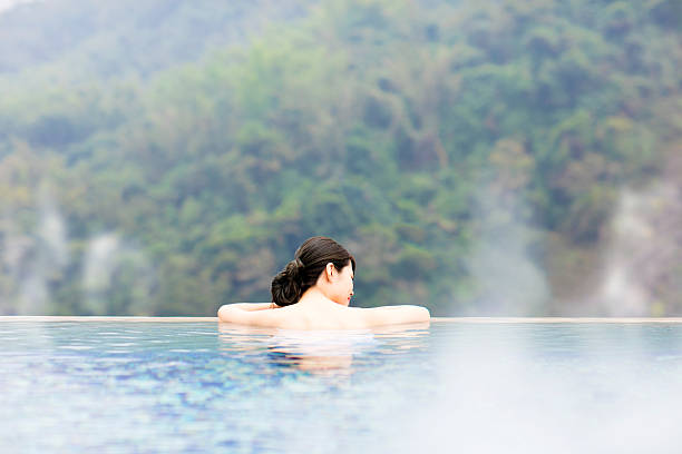 mujer joven relajándose en aguas termales - hot spring fotografías e imágenes de stock