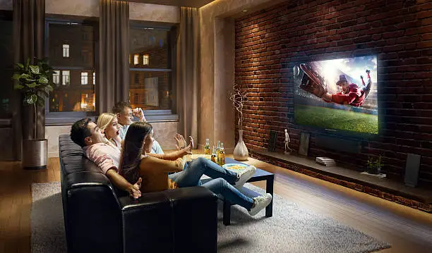 :biggrin:Two couples are cheering while watching Baseball game at home. They are sitting on a sofa in the modern living room faced to a big TV set on the front wall.