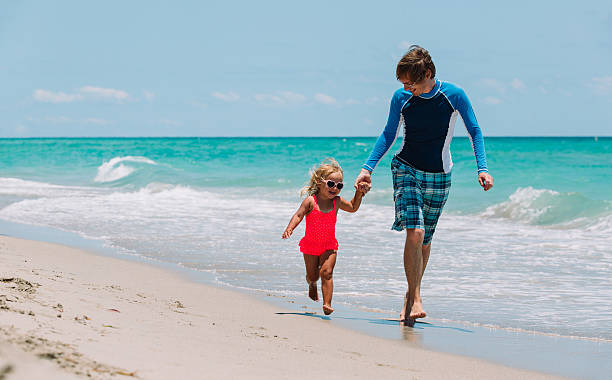 istock father with little daughter run at beach 629738570
