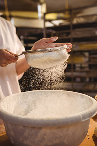 istock Mid-section of female baker sifting flour through a sieve 629743904