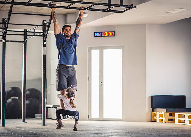 Gym time with daughter Father doing his training in gym with his little daughter on his legs. crossfit girl stock pictures, royalty-free photos & images