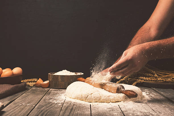 Man preparing bread dough Men hands sprinkle a dough with flour close up. Man preparing bread dough dough stock pictures, royalty-free photos & images