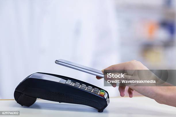 Woman Paying Bill Through Smartphone Using Nfc Technology Stock Photo - Download Image Now
