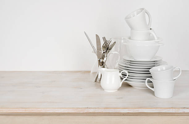 White dishware and cutlery on wooden table with copy space